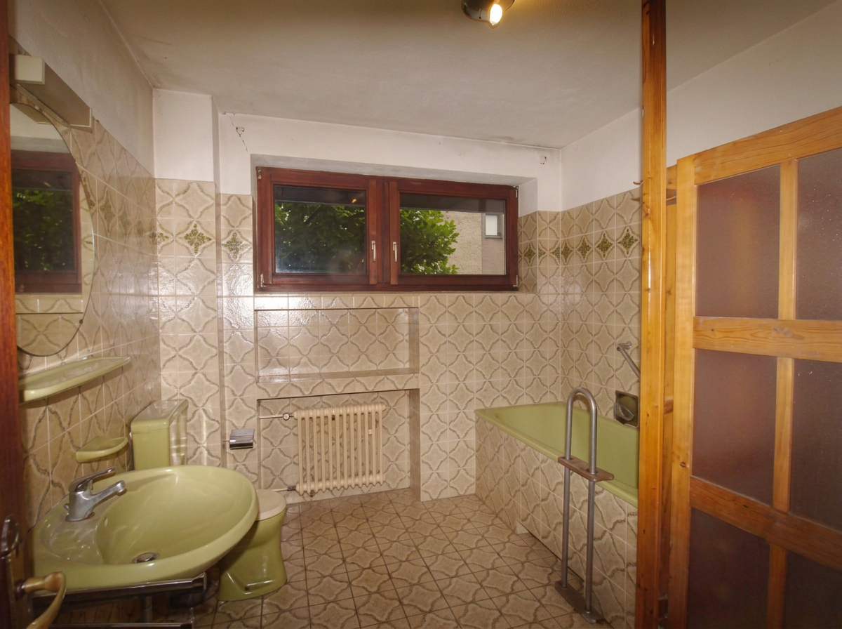 Altes Badezimmer mit grünen Sanitärobjekten und gemusterten Fliesen vor der Sanierung